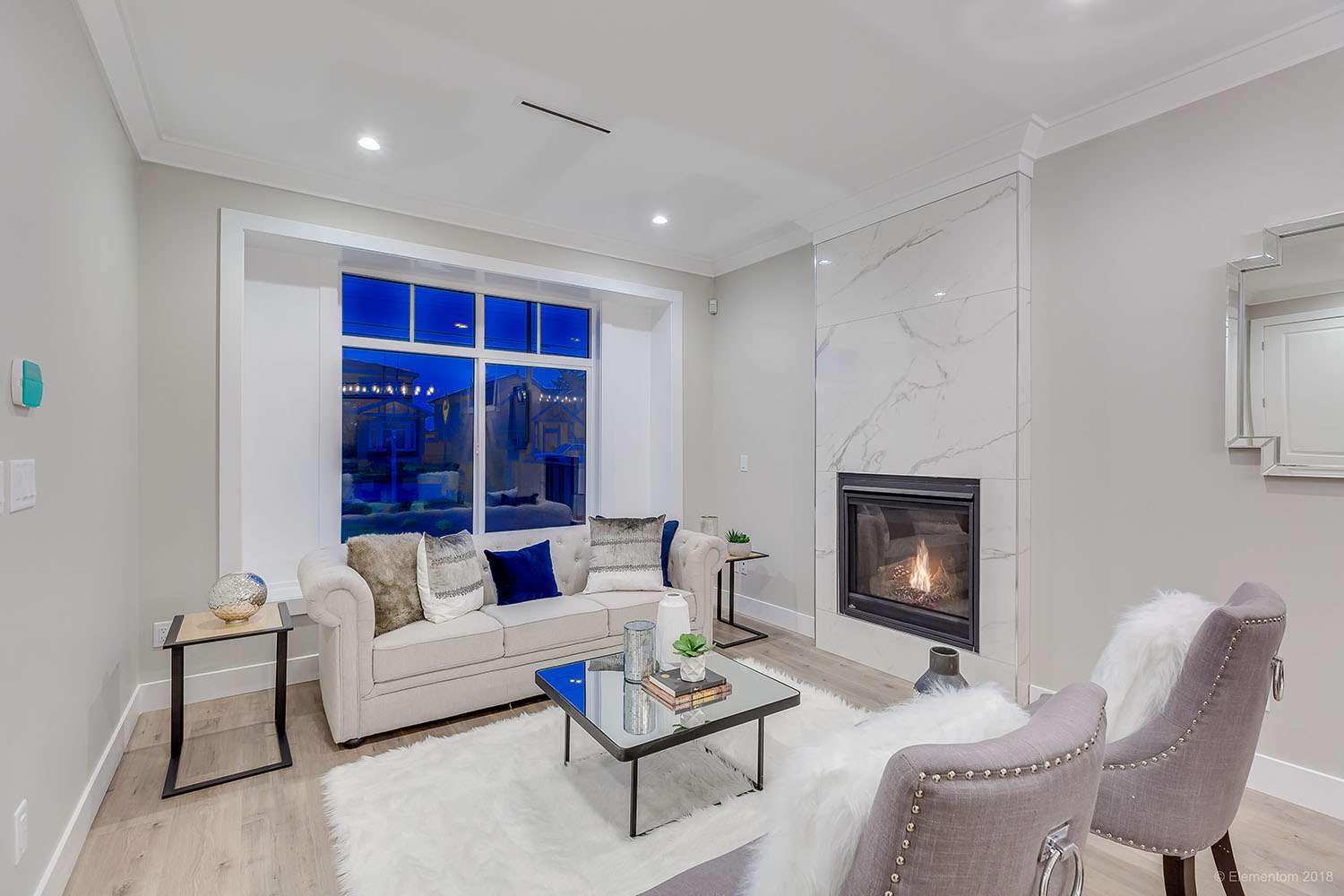 Bright living room with marble fireplace, large window and neutral furnishings in a Vancouver home