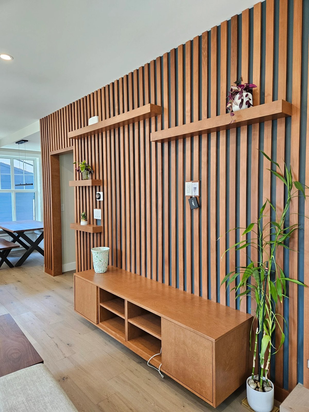 Living room with wood slat accent wall, floating shelves, and matching media console