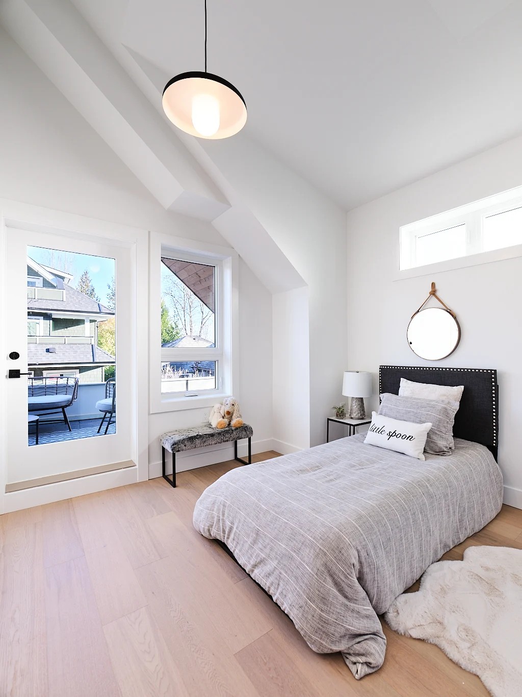 Vancouver bedroom with black nailhead headboard, round mirror, and access to covered balcony