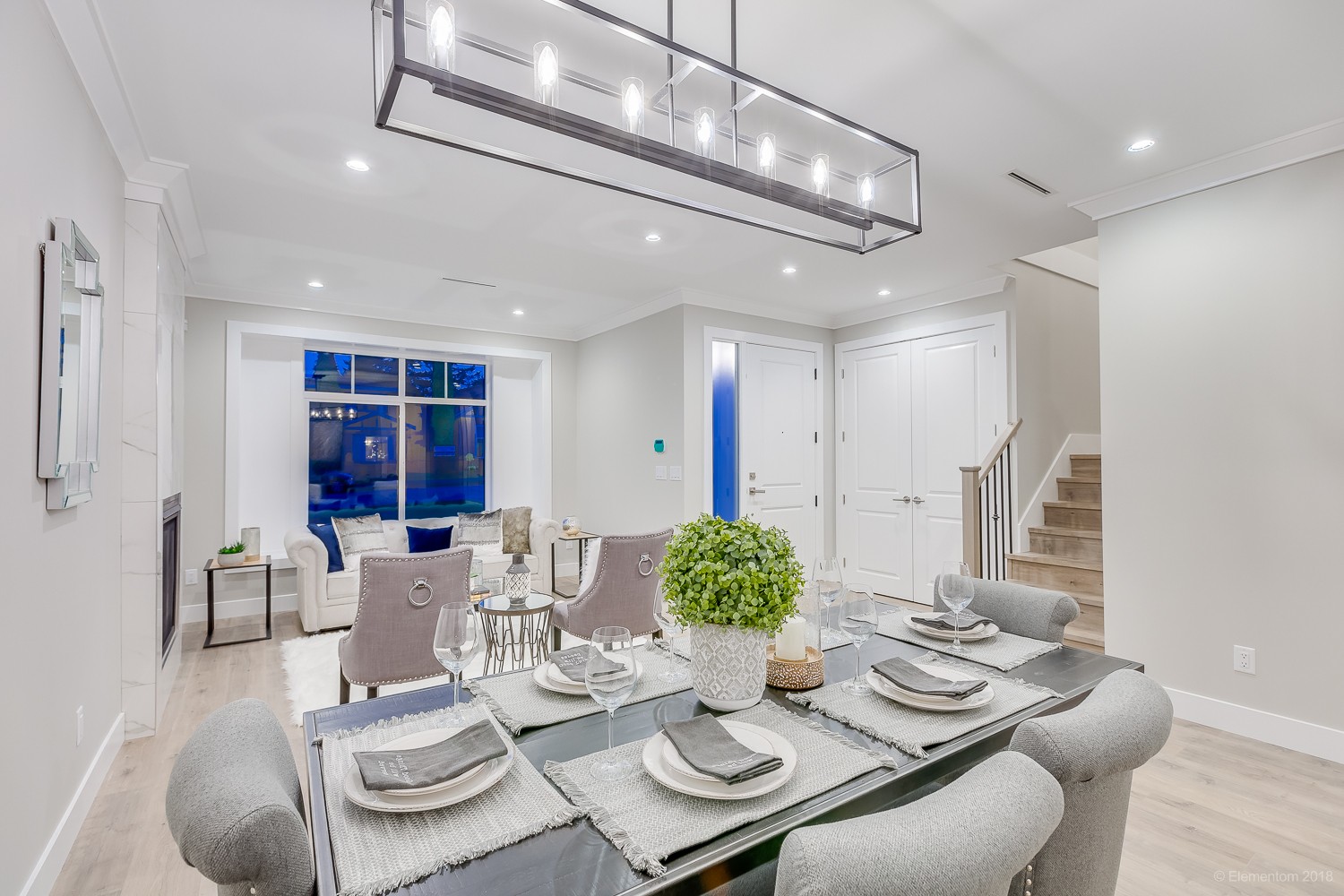 Vancouver dining room with black table, gray upholstered chairs, and linear chandelier