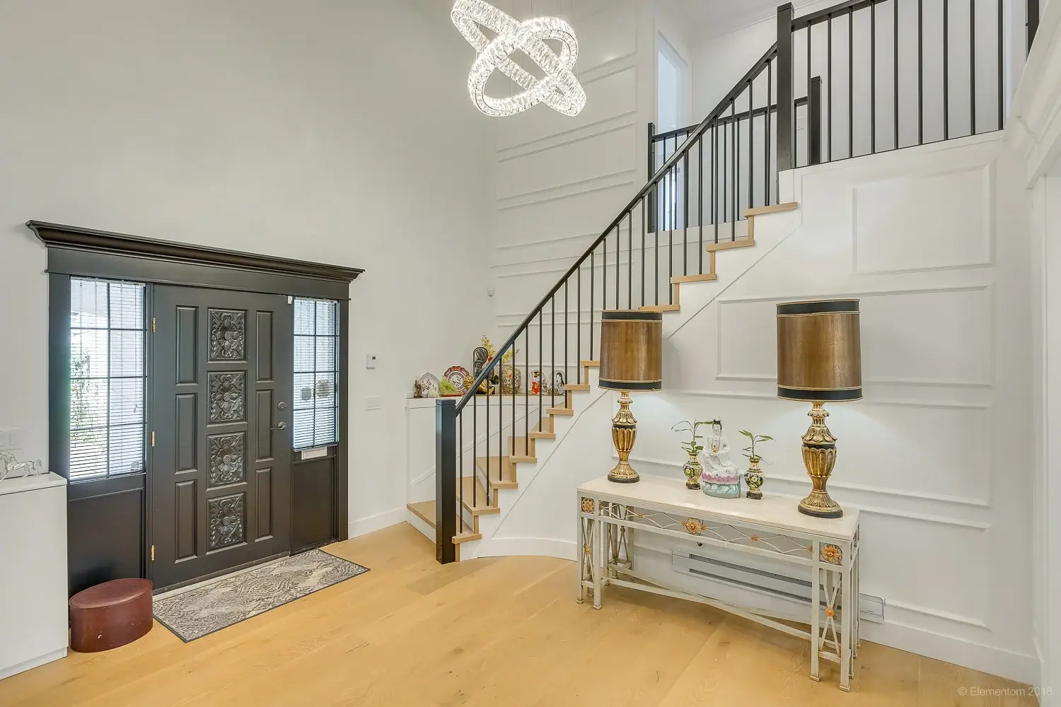 Vancouver foyer with dark carved wood front door and curved staircase