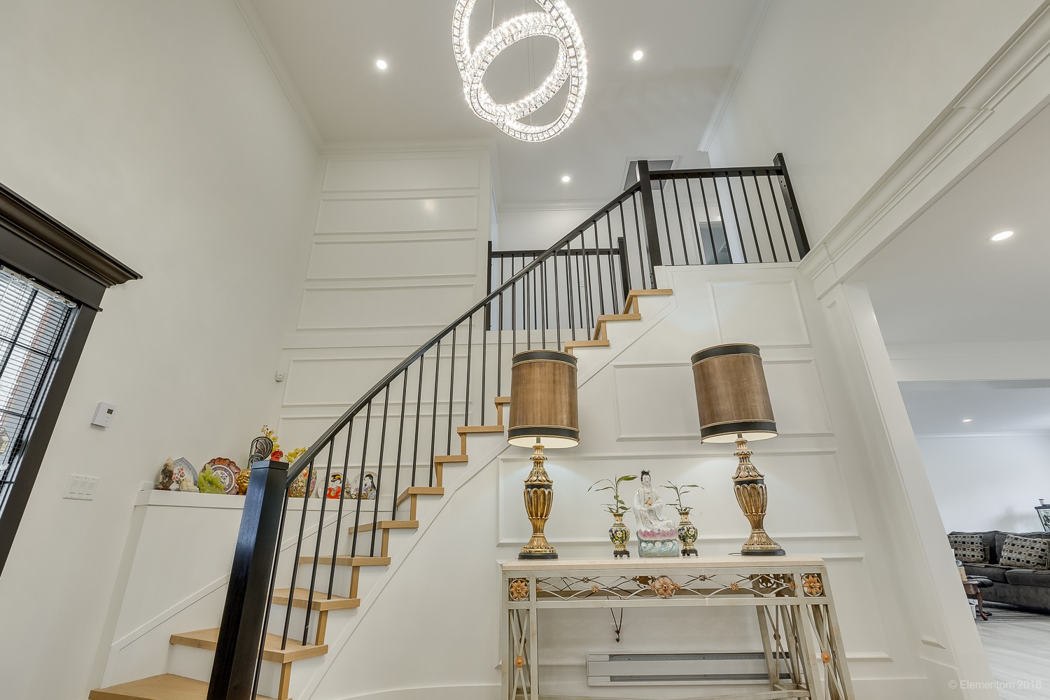 Vancouver foyer with wood staircase, wrought iron railing, and crystal ring chandelier