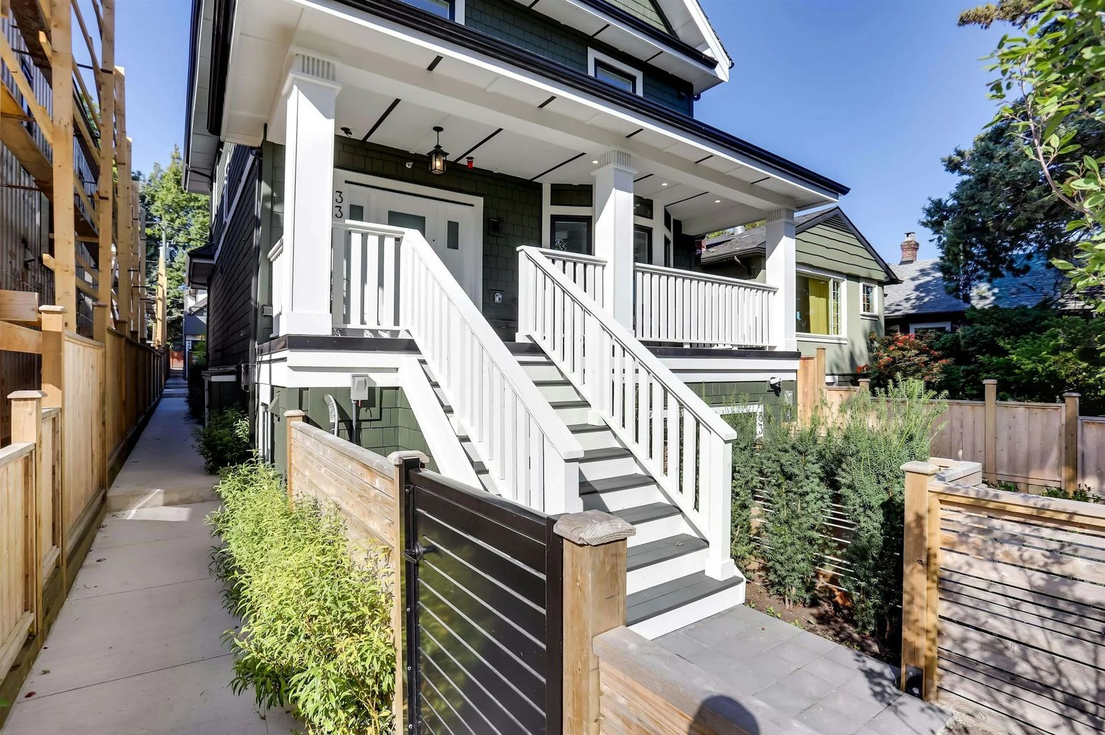 Vancouver green craftsman home exterior with white staircase and covered front porch
