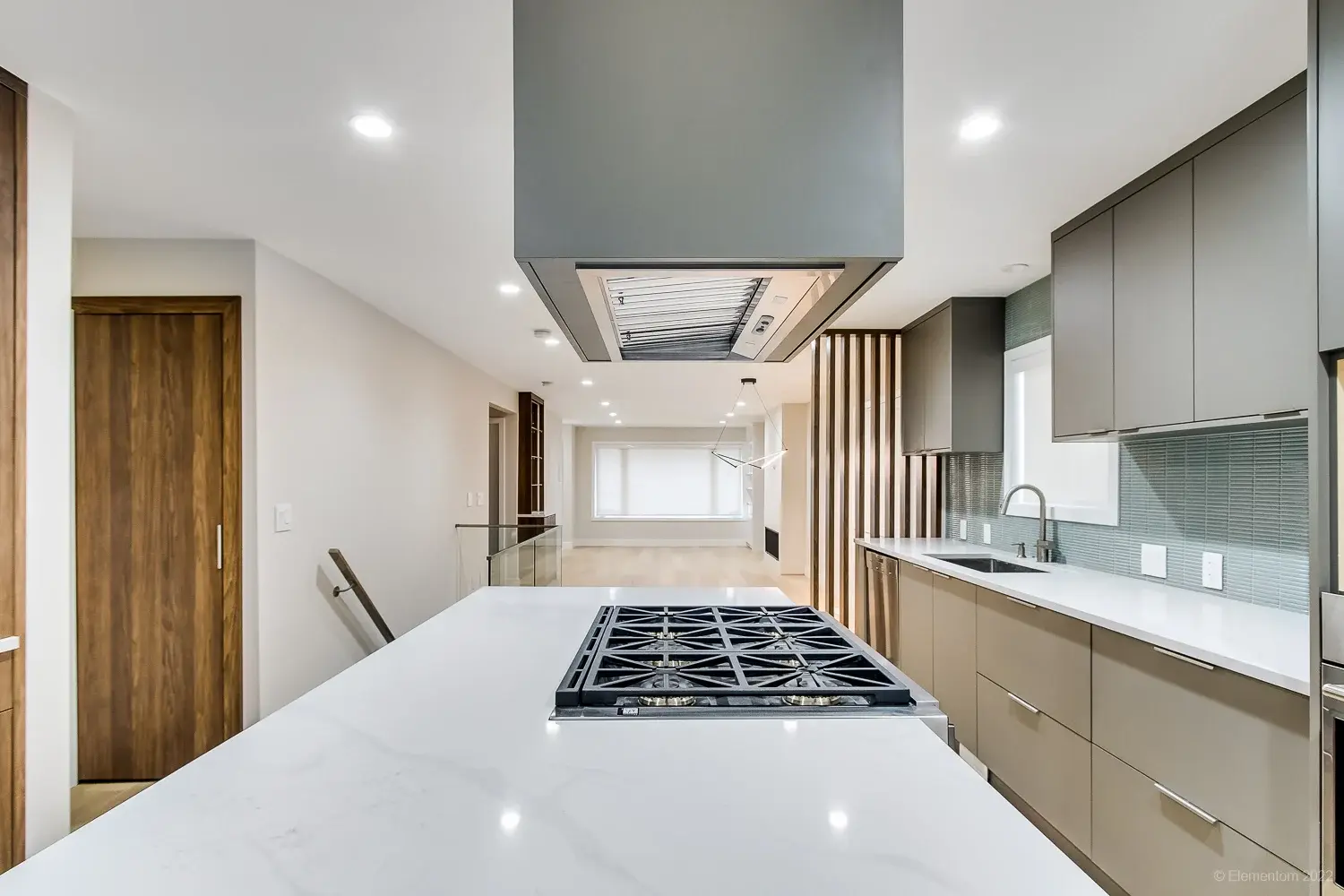 Vancouver kitchen island with gas cooktop, quartz countertops, and large stainless range hood