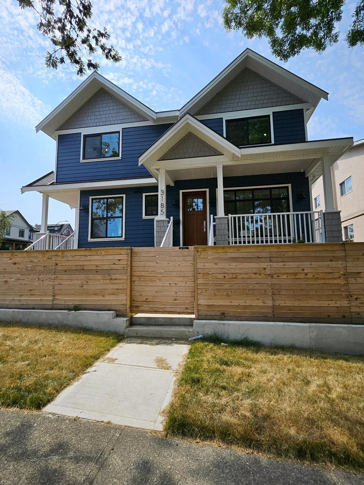 Vancouver two story navy blue craftsman home exterior with covered front porch and wood accent fence