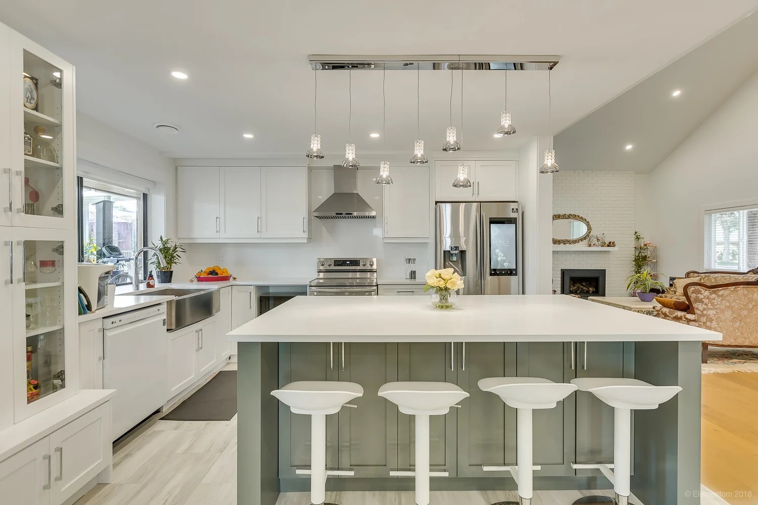 Vancouver white kitchen with sage green island, stainless appliances, and pendant lighting