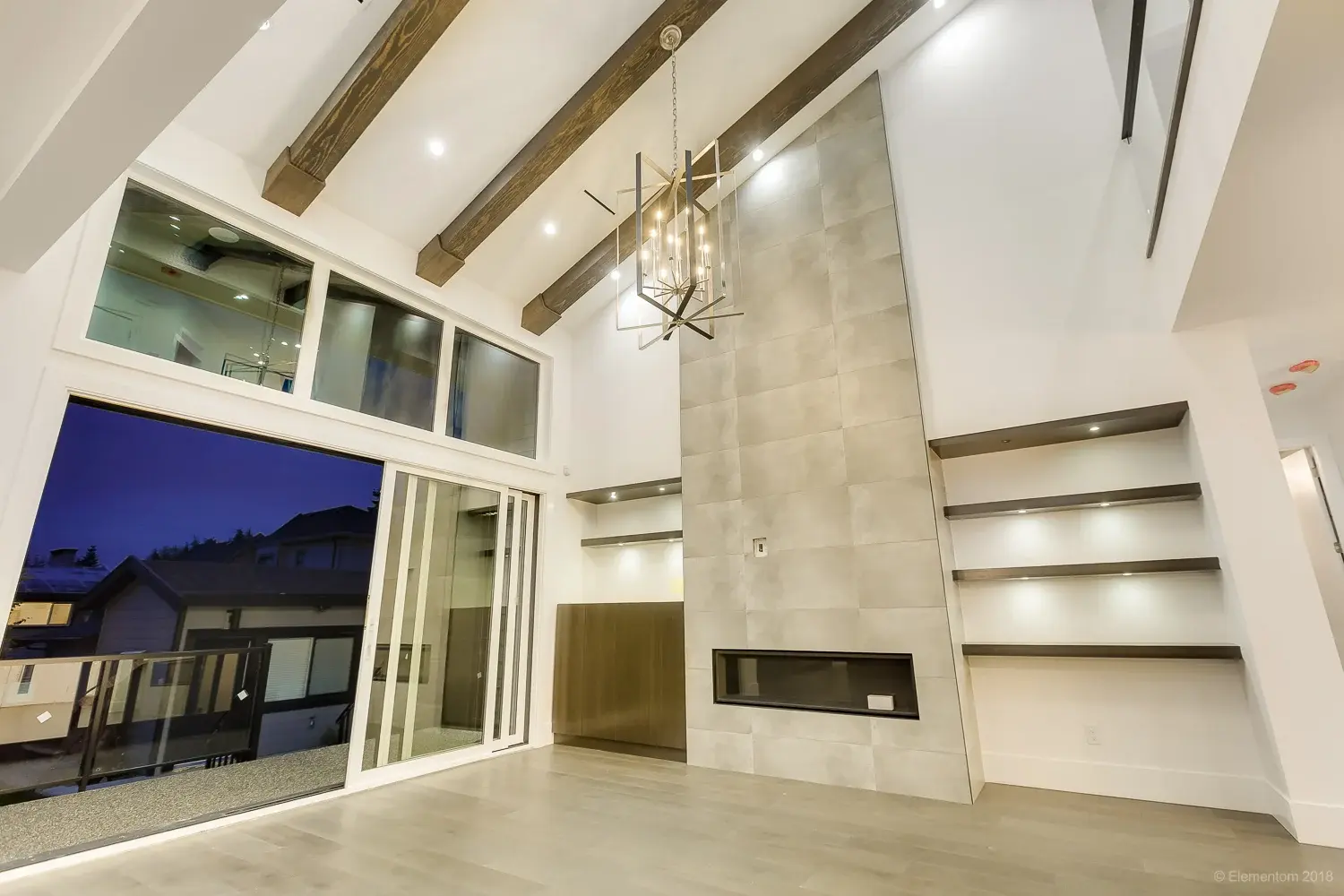 Vaulted living room with wood beam ceiling, tile fireplace wall, and built-in shelving