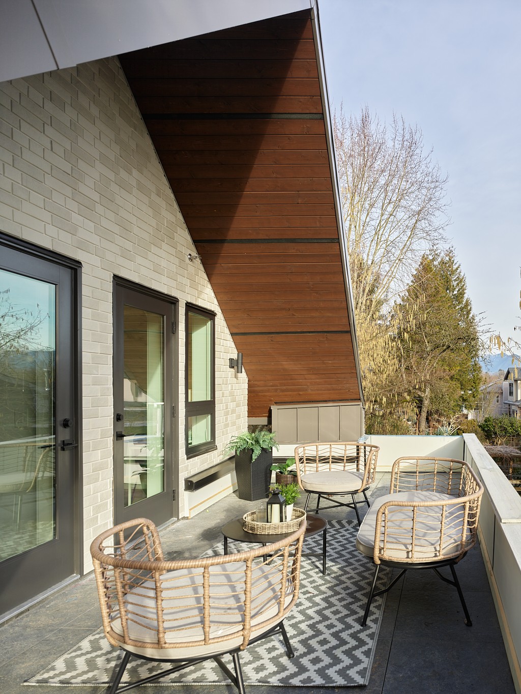 Vancouver rooftop deck with woven rattan chairs, patterned outdoor rug, and cedar accent ceiling